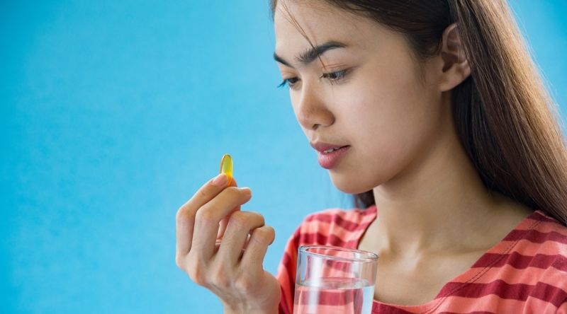 Young woman taking medicine pill after doctor order