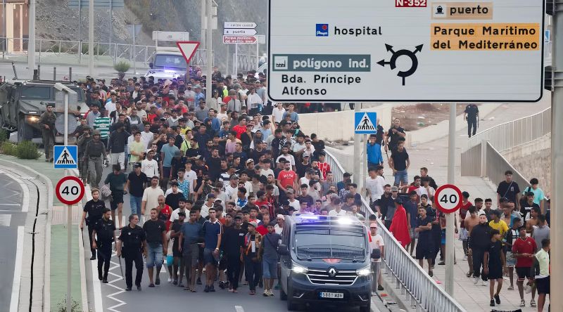 Policiais e soldados espanhóis escoltam um grande grupo de migrantes até a fronteira - Foto_ REUTERS