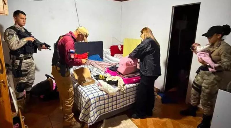 Policial paraguai com bebê no colo na casa onde foi encontrada
